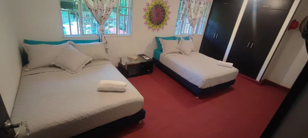 Dos camas dobles, el mandala de colores y cortinas estampadas en la habitación superior.