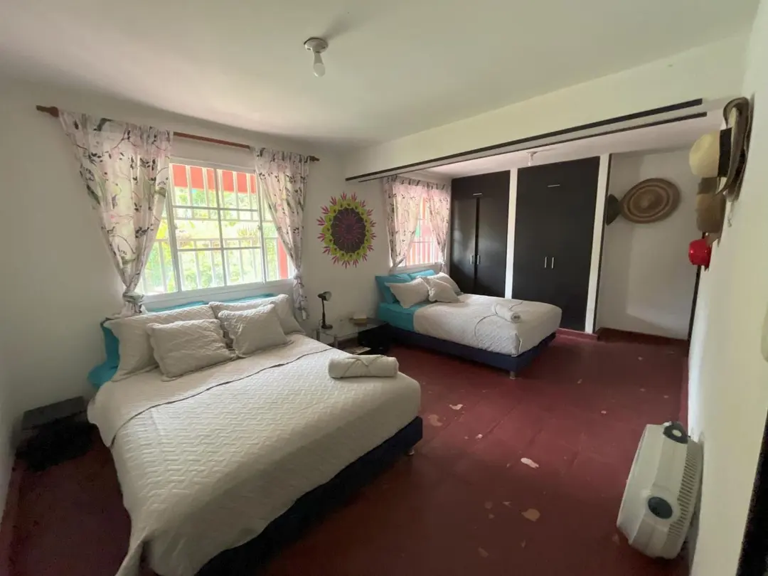 Habitación superior con dos camas, un sol decorativo en la pared y ventilador.