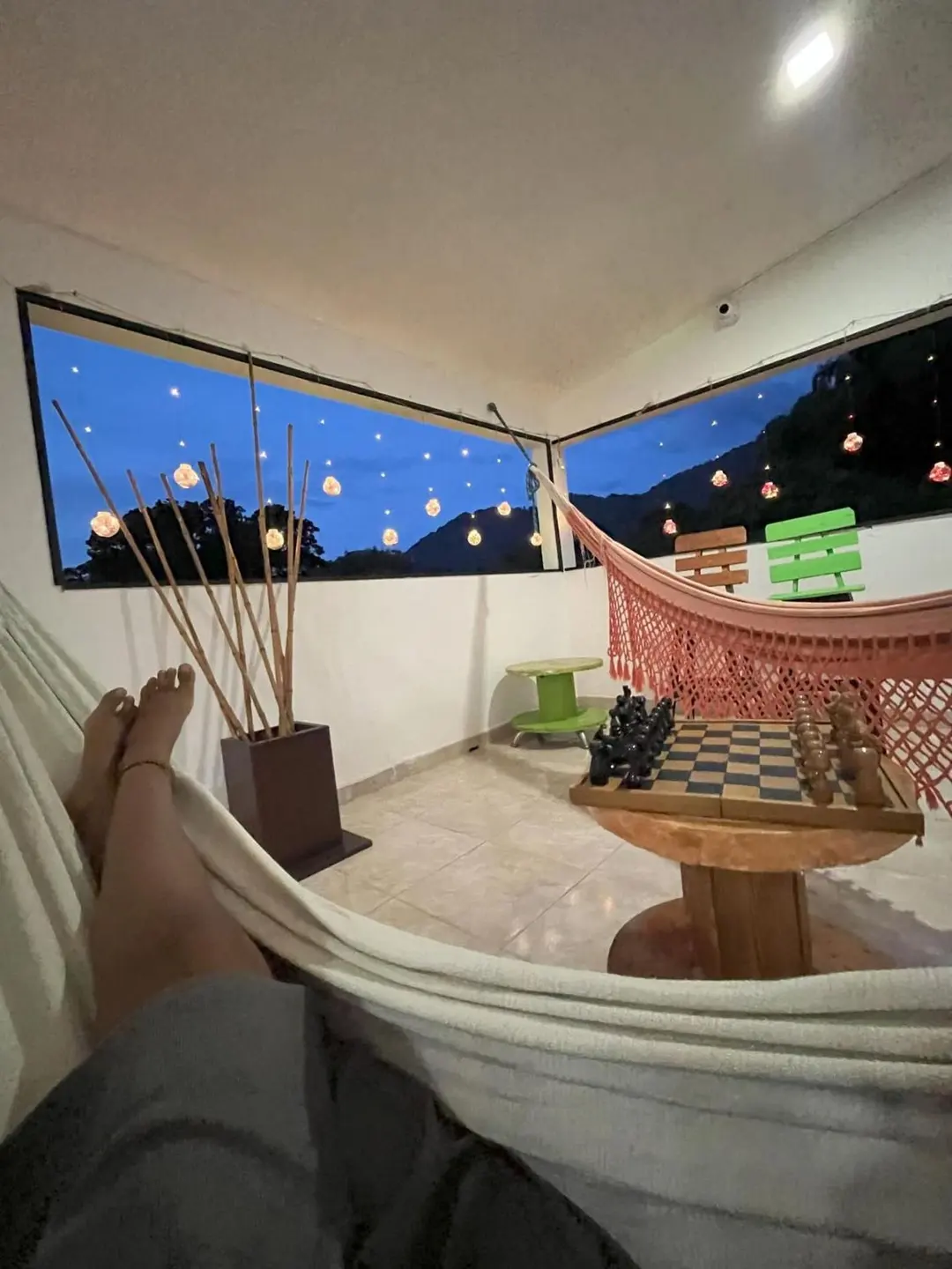 Desde una hamaca en la terraza: el tablero de ajedrez, las luces colgantes y el atardecer.
