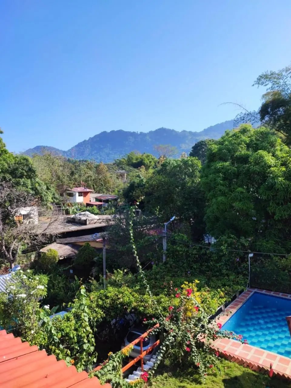 Montañas y árboles vistos desde la casa en una mañana despejada; abajo a la derecha asoma la piscina.