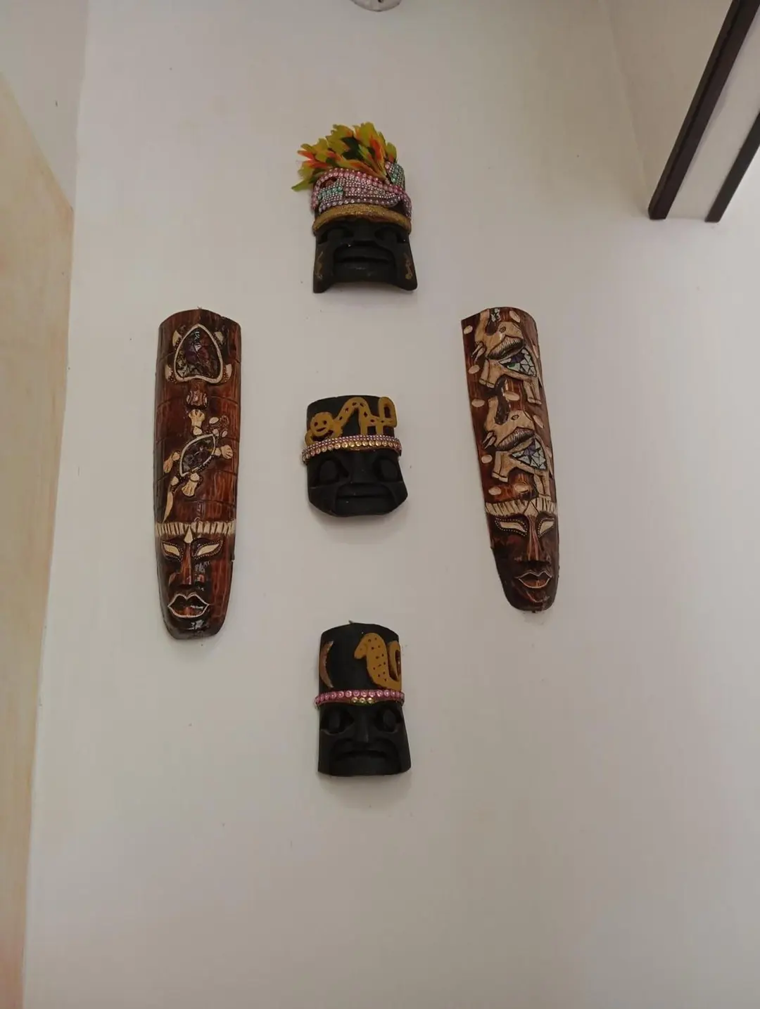Máscaras de madera talladas colgadas en una pared blanca.